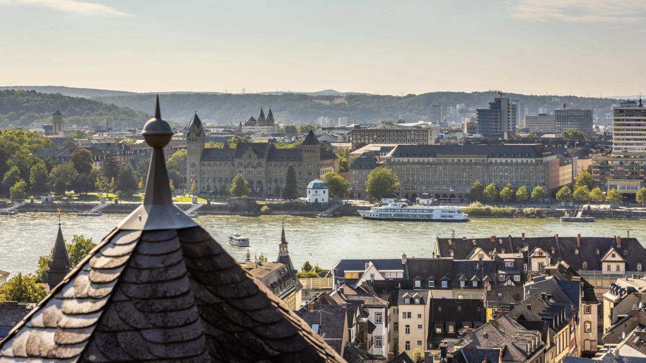 Ausblick über Koblenz vom Stadtteil Ehrenbreitstein aus mit mehreren Türmen, dem preußischen Regierungsgebäude, dem Pegelhaus und dem Rhein im Blick