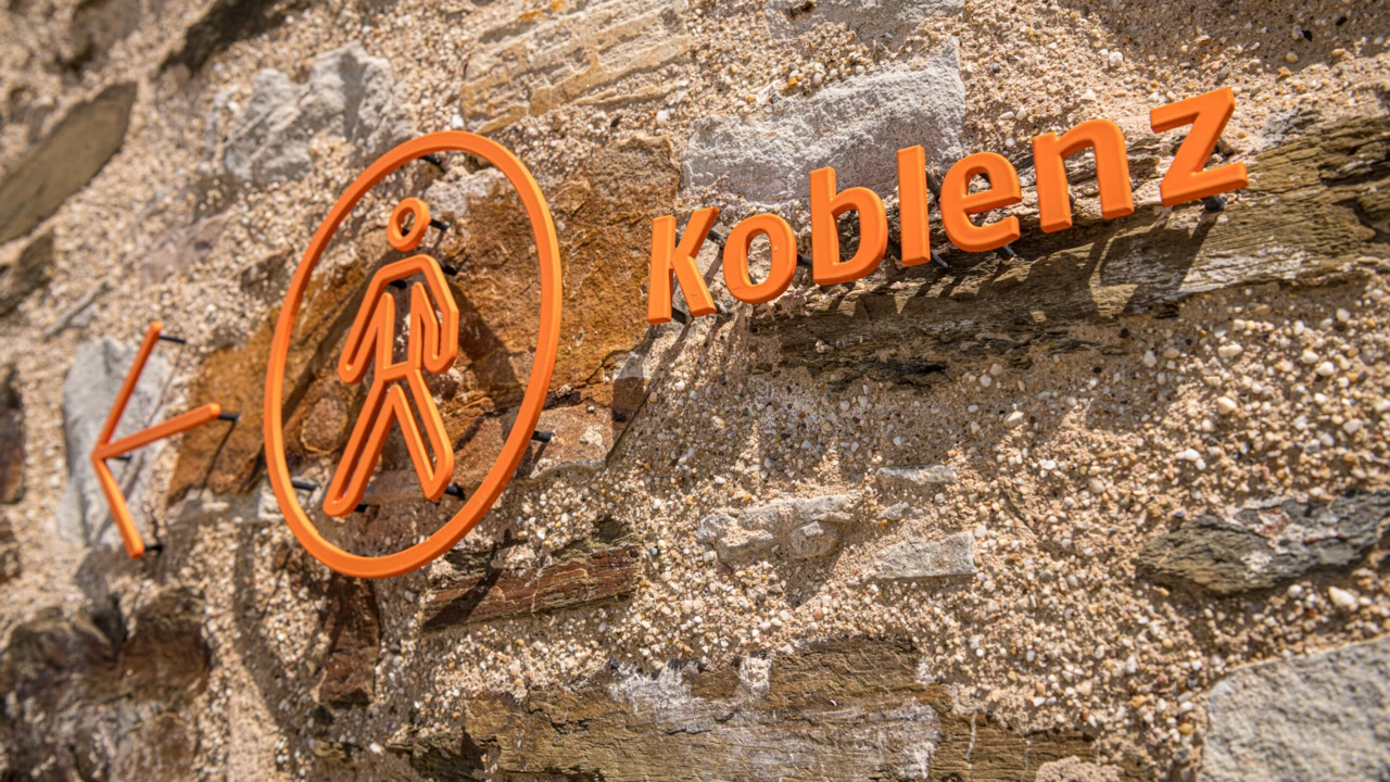 Koblenzschild an Mauer mit Pfeil in Richtung Stadt