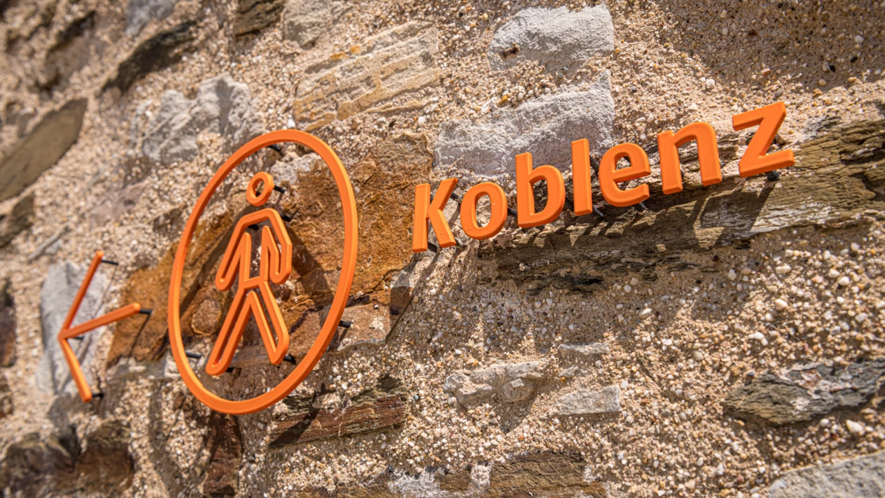 Koblenzschild an Mauer mit Pfeil in Richtung Stadt