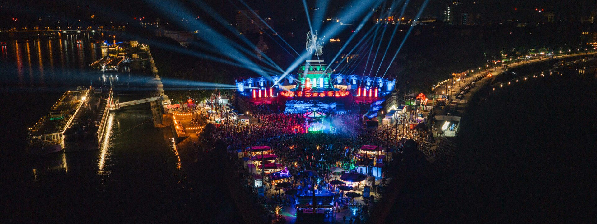 Deutsches Eck mit den Flüssen Rhein und Mosel. Darauf feiernde Menschen am Abend. © Koblenz-Touristik, Janko.Media